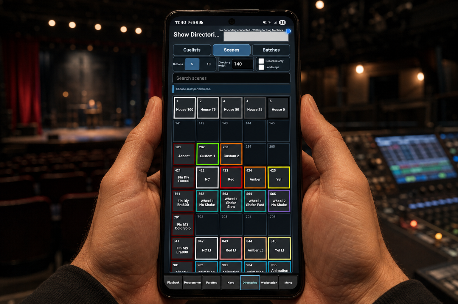 Illustrative mockup of hands holding an Android phone with HOG Link's Scenes directory in a theatre